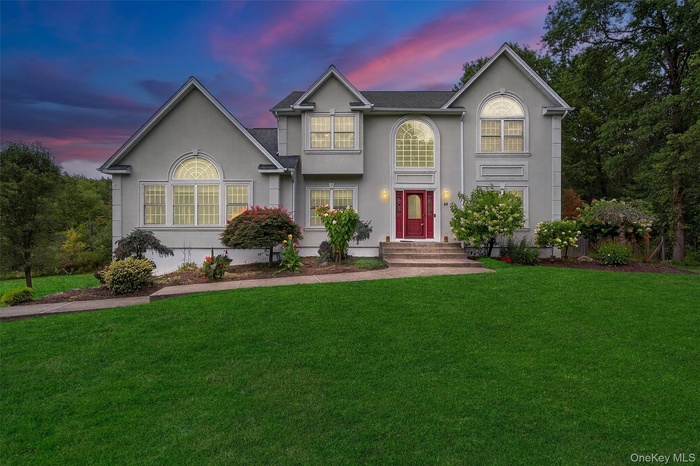 Traditional home with stucco siding and a lawn