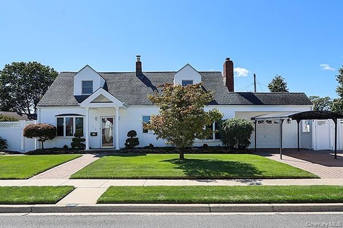 View of front of property with a chimney, a carport, and a garage