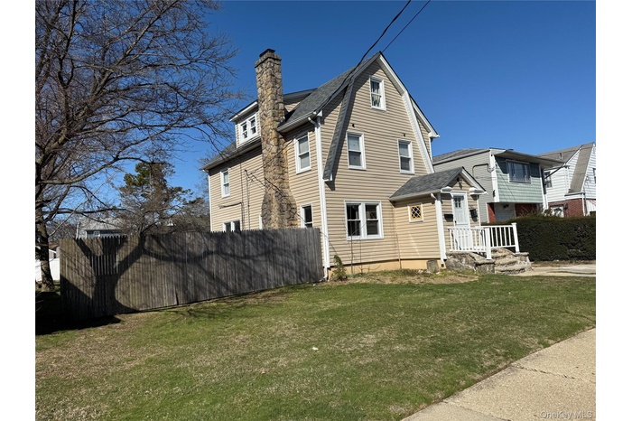 View of side of property featuring a chimney and a shingled roof
