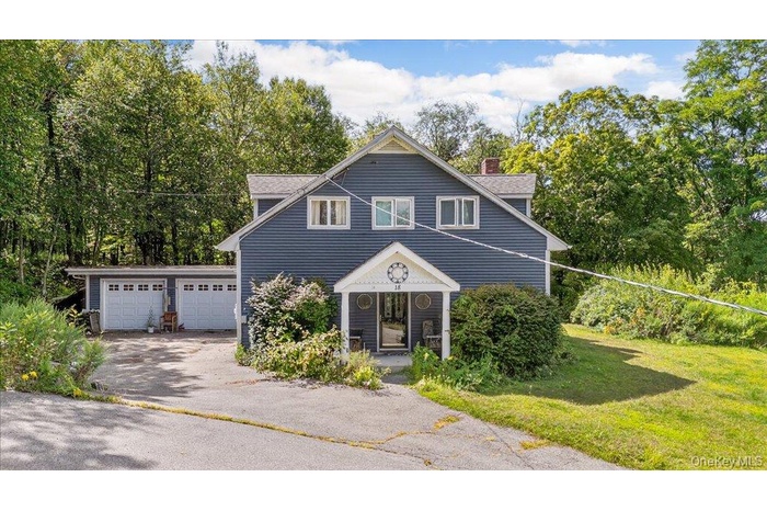 View of front of property featuring a garage, a chimney, a front yard, and driveway