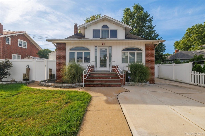 Bungalow-style home featuring brick siding, a chimney, a shingled roof, and a gate
