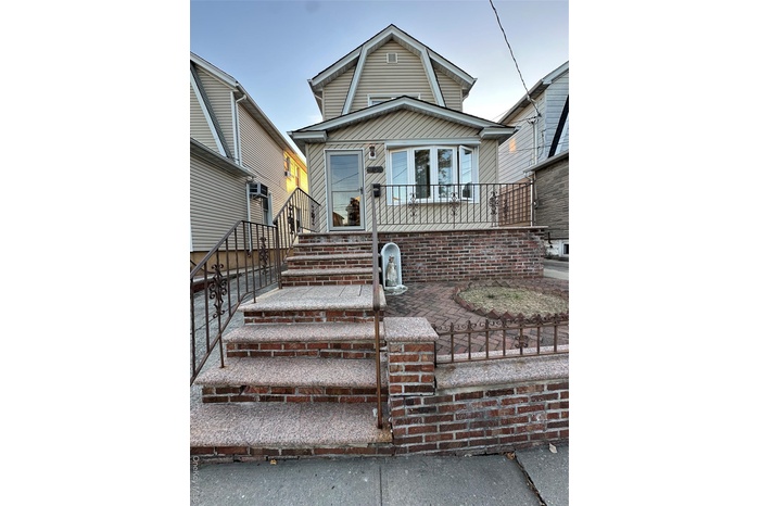 View of front of house with a fenced front yard, a gambrel roof, stairs, and a patio area