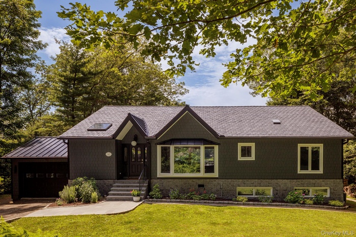View of front of home with an attached garage, a front yard, and a standing seam roof