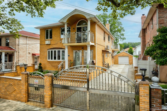 View of front of house with a gate, a fenced front yard, brick siding, and an outbuilding