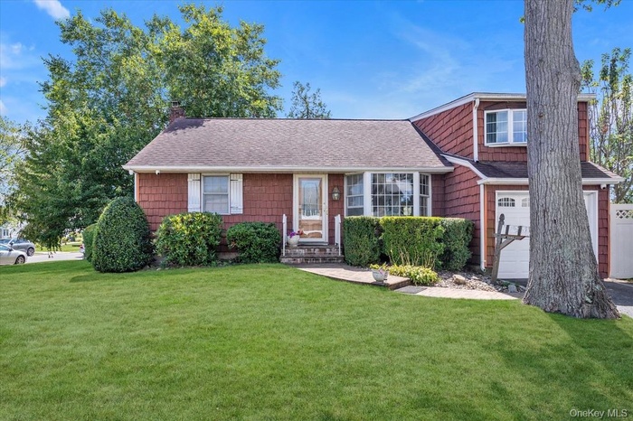 View of front of home featuring a shingled roof, a front yard, and a chimney