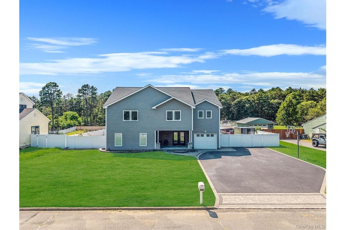 View of front of home featuring asphalt driveway, view of wooded area, and an attached garage