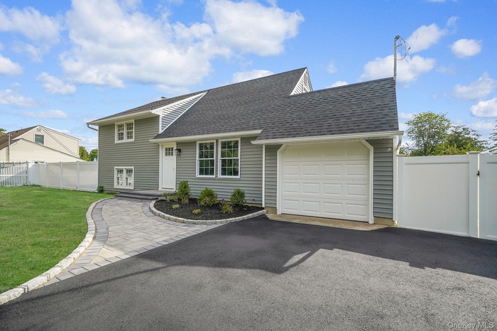 View of front of property with a garage, roof with shingles, and asphalt driveway