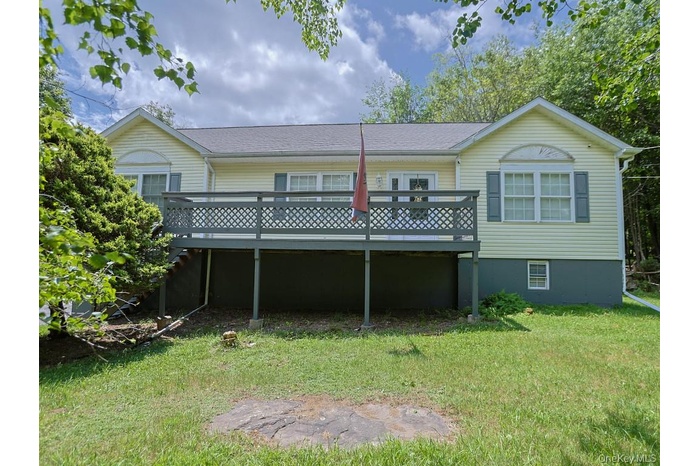 Back of house featuring a wooden deck and a yard