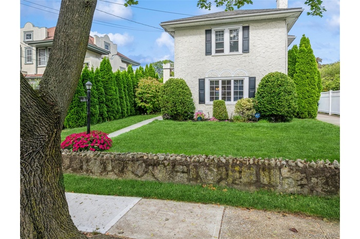 View of front of house with a front yard, stucco siding, and a chimney