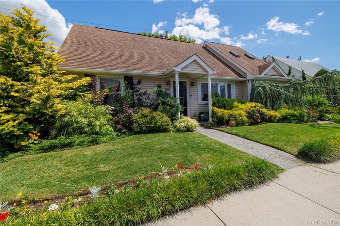View of front facade with a front lawn and a shingled roof