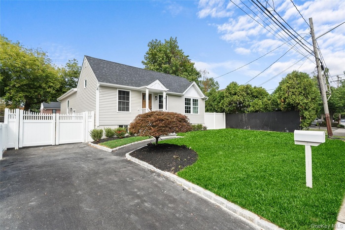 View of front of property featuring a shingled roof and a gate