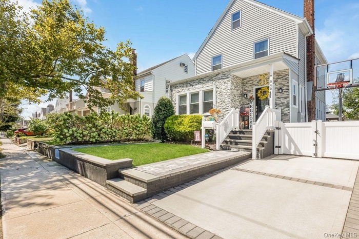 Back of property with a gate, a chimney, stone siding, and a lawn