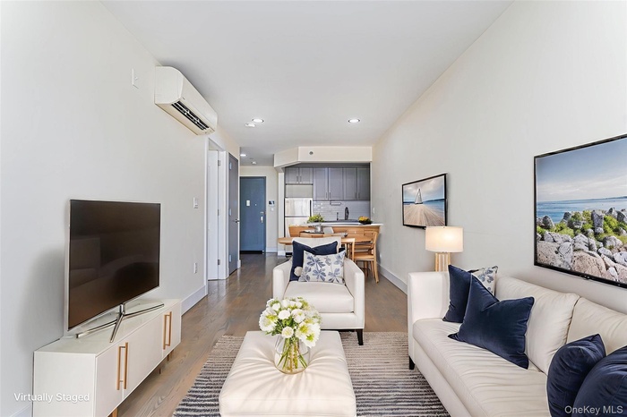 Living area with wood finished floors, recessed lighting, and an AC wall unit