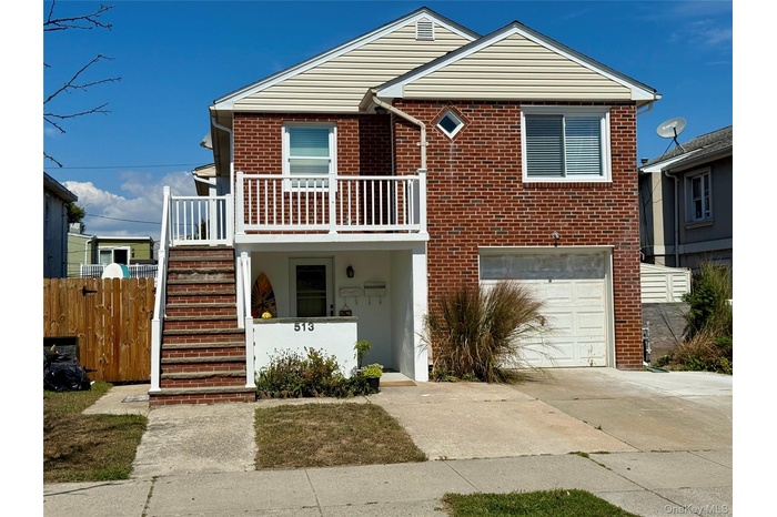 View of front facade featuring stairway, concrete driveway, brick siding, and a garage