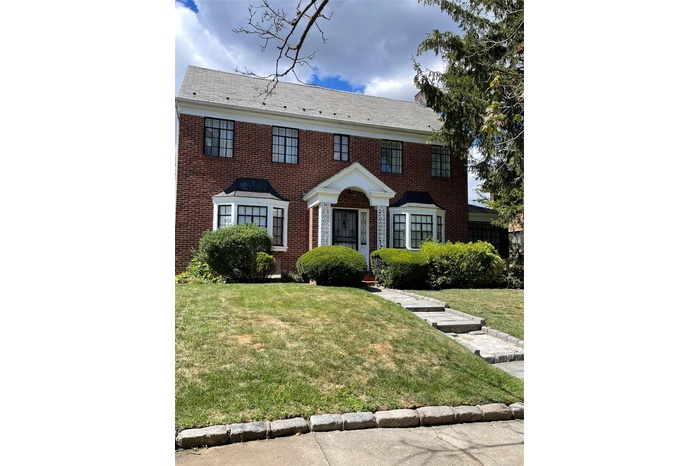 Colonial inspired home with brick siding and a front yard