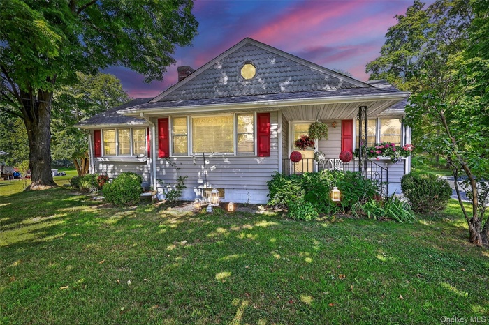 View of front facade featuring a front yard, covered porch, and a chimney