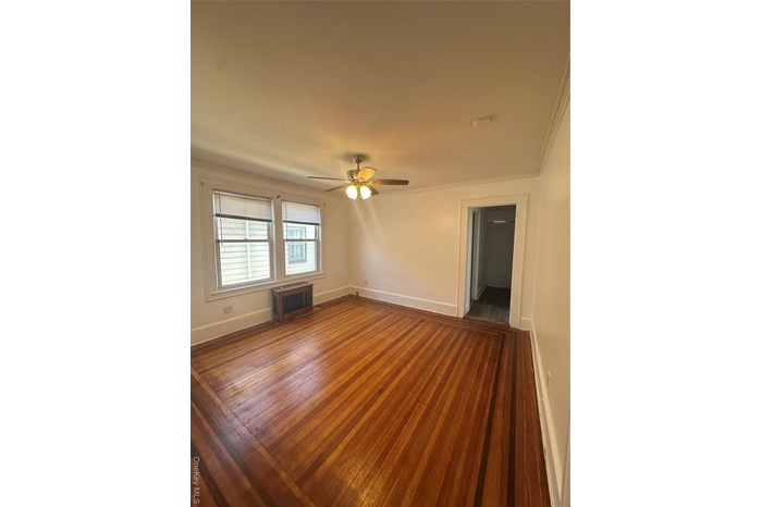 Spare room with dark wood-style flooring, ornamental molding, and ceiling fan