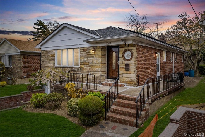 Bungalow with stone siding, a chimney, and a shingled roof