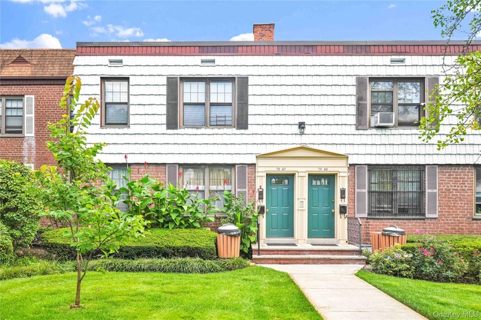 View of front of property with a front lawn, a chimney, and brick siding
