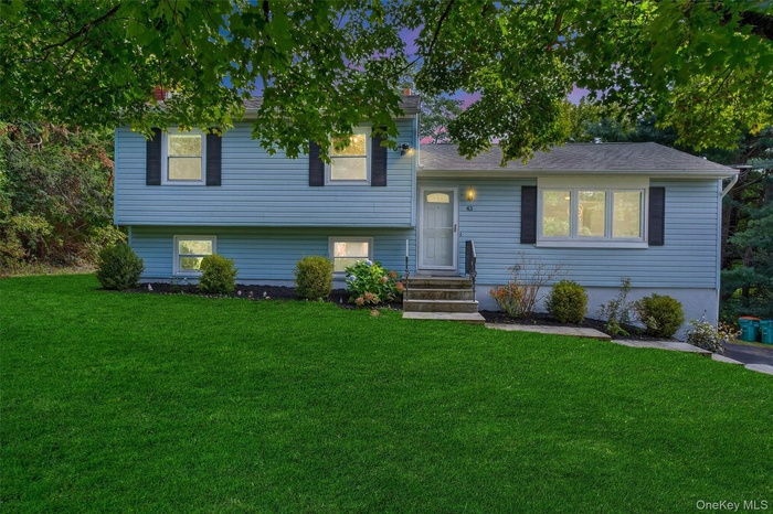 Tri-level home featuring a front lawn, entry steps, and a shingled roof
