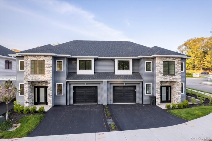 View of front of home featuring stone siding, driveway, a shingled roof, and a garage