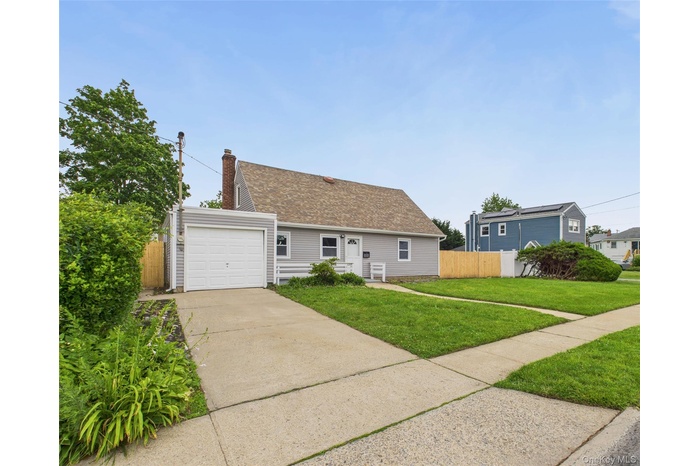 View of front of property with concrete driveway, a shingled roof, and a chimney