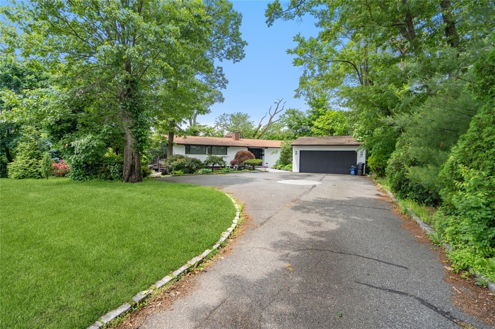 View of front of property featuring asphalt driveway, a front lawn, and a garage