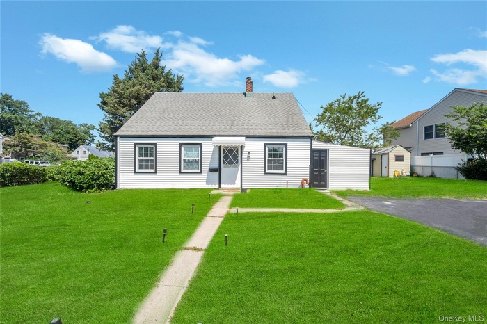 Cape cod house featuring a front lawn, a chimney, and a shingled roof