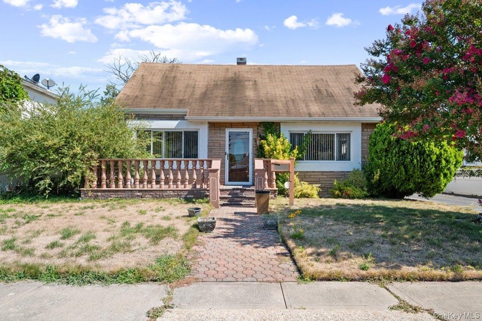 View of front of home with a shingled roof, brick siding, and a wooden deck