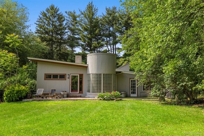 Back of house featuring a chimney, a yard, and a patio area
