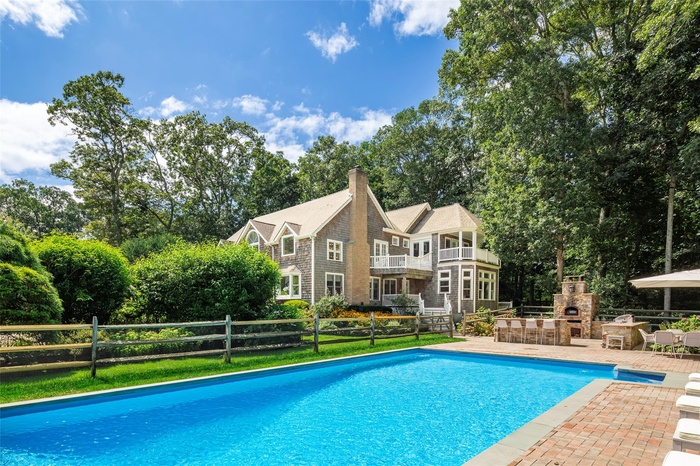 View of pool featuring an outdoor stone fireplace, fence, a fenced in pool, and a patio area