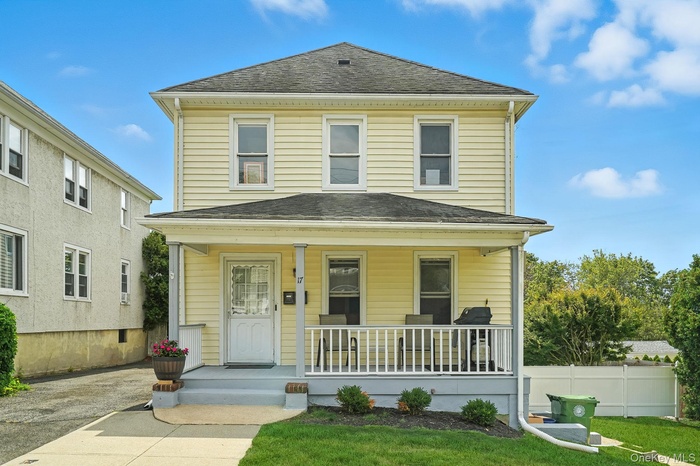 Traditional style home with covered porch, roof with shingles, and a front lawn