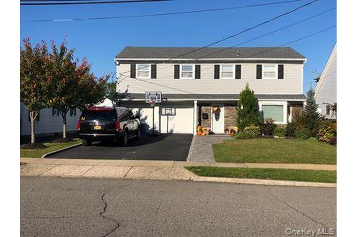 View of front of home with asphalt driveway, a front yard, and a garage