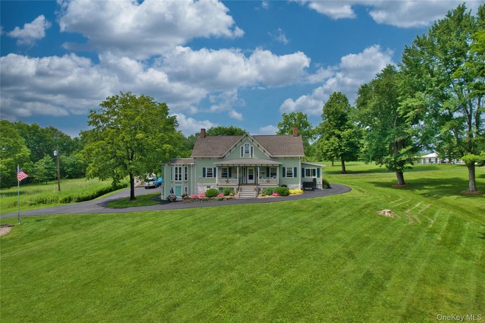 View of front facade featuring a porch, a front lawn, a chimney, and asphalt driveway