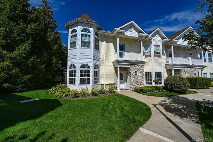 Victorian home featuring stone siding, a front yard, and a balcony