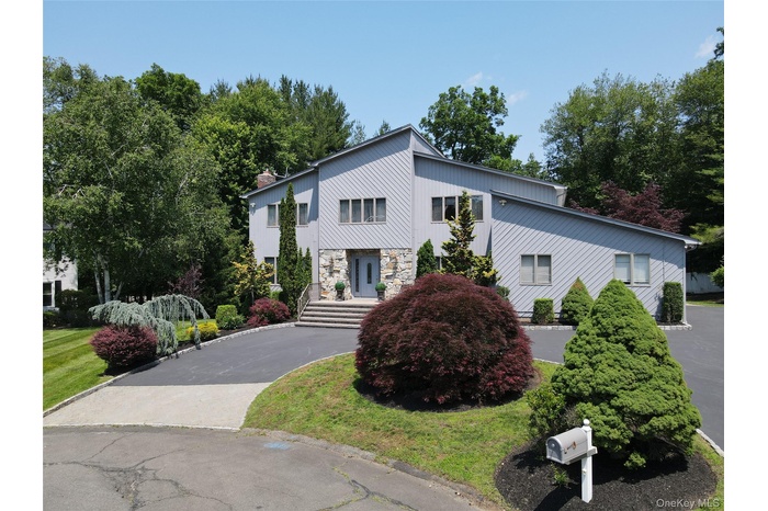 View of front of property with stone siding, asphalt driveway, and a chimney