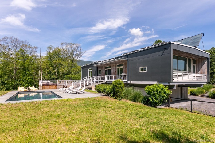 Rear view of property featuring an outdoor pool, a patio, and a lawn