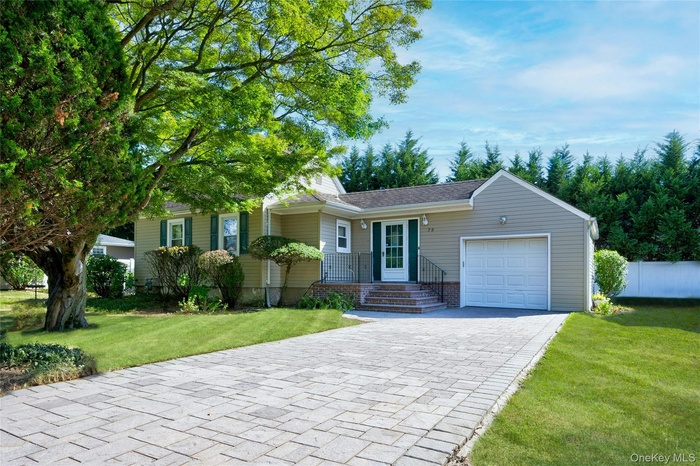 View of front of house featuring a front lawn, decorative driveway, and a garage