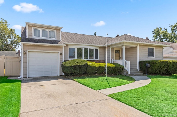 View of front of house featuring roof with shingles, driveway, an attached garage, and a gate