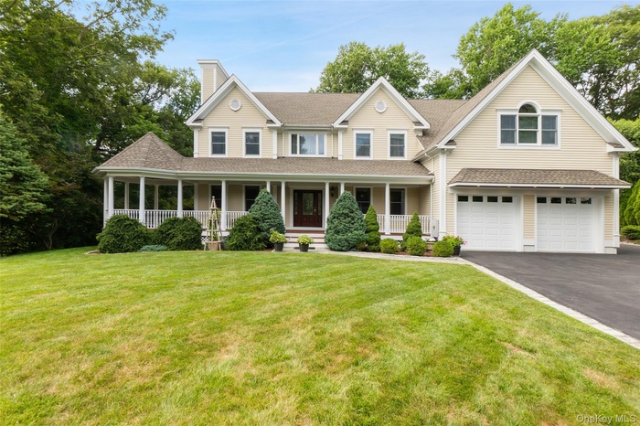 View of front of house featuring roof with shingles, a porch, a garage, driveway, and a front yard