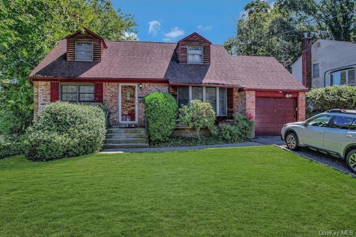 View of front of house with brick siding, a garage, a shingled roof, and asphalt driveway