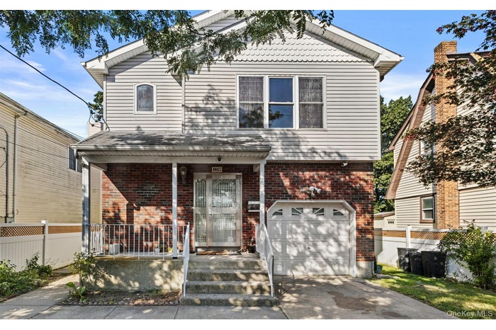 View of front of home with covered porch, a garage, driveway, and brick siding