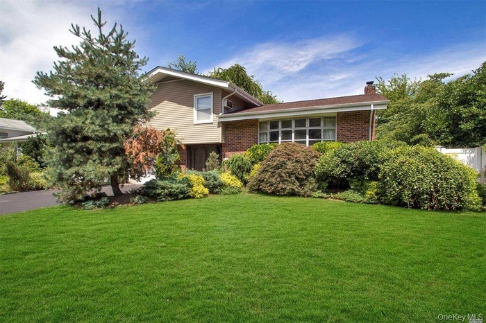 Tri-level home featuring brick siding, a front yard, and a chimney