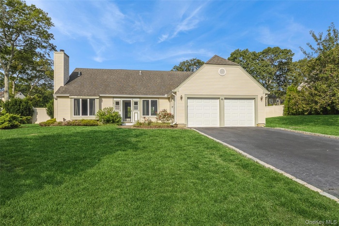 View of front of house featuring driveway, a chimney, roof with shingles, and a garage