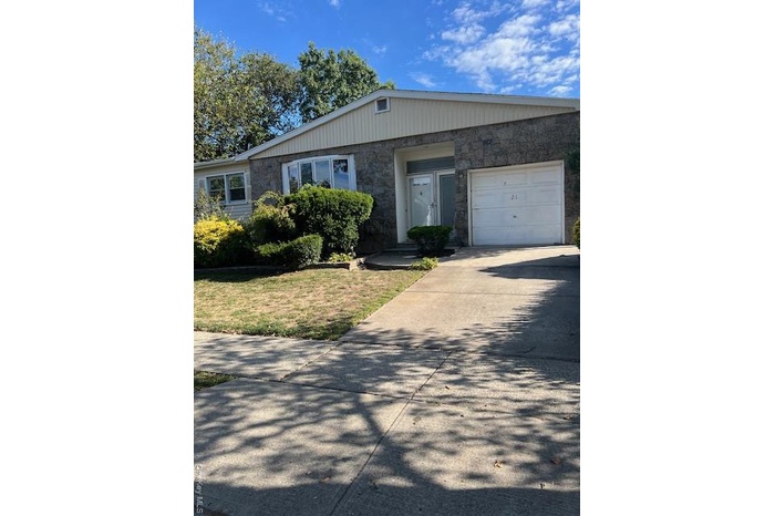 View of front of house with stone siding, concrete driveway, a garage, and a front yard