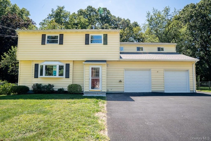 Colonial house with driveway, a garage, and a front yard