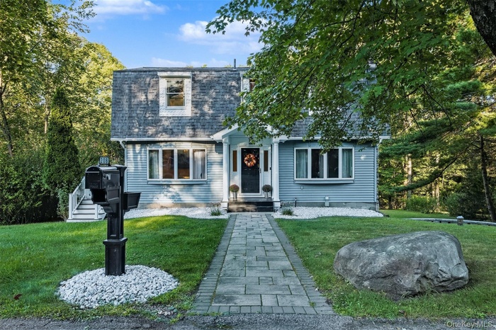View of front of property featuring a front yard, mansard roof, and roof with shingles