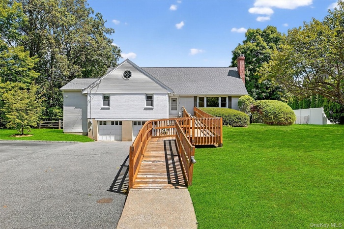 View of front of home with a shingled roof, driveway, an attached garage, a chimney, and stairway