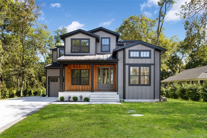 View of front of property featuring board and batten siding, a porch, a standing seam roof, a metal roof, and a front lawn