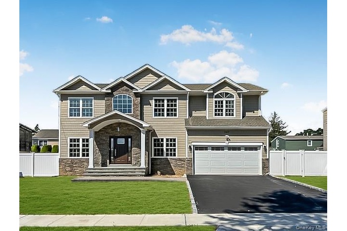Colonial home with front porrtico, paver walkway, vinyl sided with stone accent.